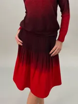 Falda midi de crepe de lana, teñida a mano con degradado de bordó a rojo, con bolsillos laterales y tablas.