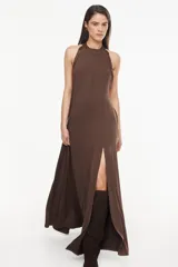 Vestido largo azul marino, de corte fluido, con escote halter, detalles trenzados en los hombros, bolsillos laterales y tajo profundo en la pierna.