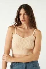 Top tejido de punto color beige, con escote corazón y breteles finos. Presenta una textura acanalada y un corte corto al cuerpo.