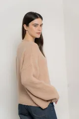 Sweater de punto con textura suave, color beige, de corte holgado y mangas largas con terminación de cuello y puños en estilo rulé.