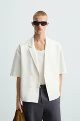 Camisa blanca de manga corta con cuello de solapa de muesca y cierre cruzado de doble botonadura.