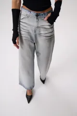 Pantalón de jean celeste con efecto desgastado, corte ancho, tiro alto y largo hasta los tobillos.
