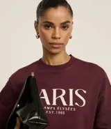 Saco de algodón color bordó con cuello redondo y mangas largas. Tiene ribete en cuello, puños y bajo. Estampado frontal con la leyenda "Paris - Champs Élysées - Est. 1965".