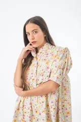 Vestido corto verde con estampado floral, cuello alto, mangas cortas abullonadas y corte holgado.