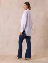 Camisa blanca de lyocell, marca Hester & Orchard. Tiene cuello con solapa, abertura central con botones, bolsillo aplicado en el pecho y ruedo desflecado.