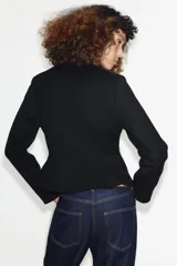 Cazadora de cuello redondo y manga larga con diseño peplum en el bajo. Presenta cierre frontal con cremallera metálica.
