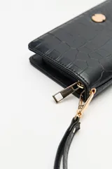 Billetera de mano con textura efecto cocodrilo, color beige, con cierre perimetral y tira de muñeca desmontable.