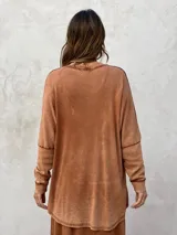 Remera de algodón con efecto lavado, cuello en V y bolsillo frontal con textura acanalada. Presenta un corte holgado con dobladillo asimétrico, más corto adelante y más largo atrás.