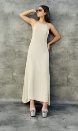 Vestido largo color beige con textura de plumetie, escote halter y espalda descubierta.