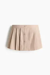 Short pollera de sarga color beige con diseño tableado, tira frontal con botones forrados decorativos y sutiles rayas finas.
