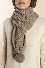 Bufanda tejida a mano en punto arroz color crudo, con detalle de pompón en uno de los extremos.