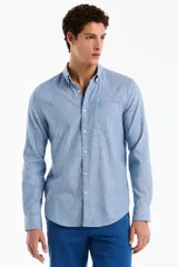 Camisa de manga larga confeccionada en mezcla de lino y algodón, color celeste melange, con cuello camisero abotonado, cierre frontal de botones y un bolsillo aplicado en el pecho con el logo bordado.