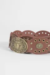 Cinturón de cuero marrón compuesto por piezas circulares unidas, decoradas con tachas metálicas doradas y apliques centrales con relieve de cabeza de toro. Incluye una hebilla metálica circular grande con diseño grabado.
