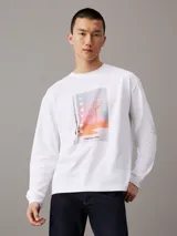 Remera de manga larga color blanco, con cuello redondo y corte relajado. Presenta un estampado fotográfico digital en el pecho con motivos de básquetbol y el logo de la marca.