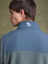 Campera de polar con cierre frontal completo, cuello alto y bolsillo en el pecho con cierre. Presenta un diseño combinado con paneles de tela técnica en la parte superior y polar en el resto de la prenda, con logo de la marca Benson & Thomas estampado en el hombro.