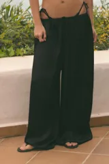 Pantalón de tiro medio, color negro, confeccionado en tejido satinado con diseño de pierna ancha y cintura elástica ajustable con cordón.