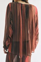 Camisa semitransparente de manga larga con diseño de rayas verticales en tonos marrones y naranjas, escote en V y cierre frontal con botones.