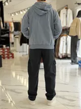 Canguro oversize beige con capucha y cordones ajustables, bolsillo tipo canguro y pequeño bordado en el pecho.