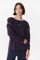 Remera de manga larga con corte oversized, color azul marino con cuello redondo en contraste color marrón. Presenta costuras decorativas a contratono hechas a mano en la zona de los hombros y logo bordado en el centro del pecho.