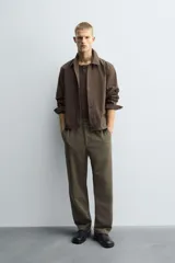 Pantalón regular fit color marrón oscuro, confeccionado en tejido con viscosa. Cuenta con cintura elástica, bolsillos delanteros y detalle de bolsillos traseros de vivo. El cierre frontal es con cremallera y botón.