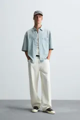 Camisa de corte relajado confeccionada en tejido de algodón, con estampado de cuadros pequeños en tonos celestes y blancos. Presenta cuello solapa, manga corta y bolsillo plastrón en el pecho con cierre frontal de botones.