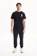 Pantalón de jogging negro sin friza, con puños elastizados en los tobillos y cordón ajustable en la cintura.