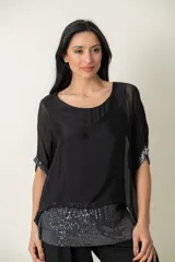 Blusa de seda negra con corte holgado, cuello redondo y mangas cortas tipo kimono. Presenta detalles de lentejuelas en los bordes de las mangas y en el ruedo inferior.
