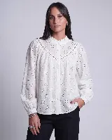 Camisa de broderie blanca con detalles calados, cuello alto con volado, cierre frontal de botones y mangas largas con puños.