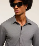 Camisa de manga larga color celeste, corte slim fit, con cuello inglés y cierre frontal de botones.