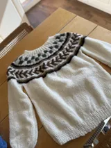 Sweater tejido a mano en lana mohair premium, color celeste con diseño geométrico en blanco, rosa y marrón.