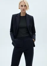 Pantalón de traje tiro medio, color azul marino, de diseño recto con trabillas, cierre oculto de botón, gancho y cremallera, dos bolsillos laterales y dos bolsillos de ribete en la parte posterior.