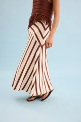 Pollera larga de punto en color beige con rayas verticales marrones, corte evasé y diseño asimétrico en la cintura.