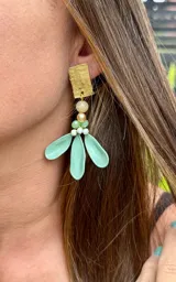 Caravanas colgantes con base rectangular de metal dorado texturizado, decoradas con cuentas de cristal en tonos crema y verde, y tres pétalos de resina en color verde menta.