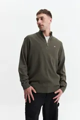 Buzo de tejido de punto color verde oliva, con cuello alto y cierre frontal parcial. Presenta un pequeño logo bordado en el pecho.