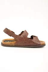 Sandalias de cuero color marrón con textura trenzada, plantilla anatómica de corcho y suela dentada. Posee tres tiras ajustables con hebillas metálicas y tira en el talón.
