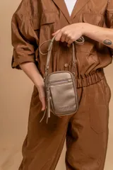 Bandolera compacta color rosado, con correa regulable y desmontable. Tiene apertura superior, bolsillo frontal con cierre y detalle de borla, y bolsillo trasero sin cierre. El interior está forrado en tela y cuenta con un bolsillo adicional.