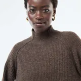 Sweater de punto canalé en color marrón, con cuello alto y mangas largas con puños ajustados. Presenta un diseño de corte holgado y tejido texturizado.