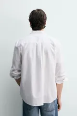 Camisa de corte regular fit en color azul, confeccionada en mezcla de lyocell y algodón, con cuello camisero, manga larga con puños abotonados, cierre frontal con botones y un bolsillo aplicado en el pecho.