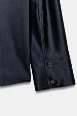 Camisa de manga larga confeccionada en tejido satinado, con cuello solapa, cierre frontal con botones y bajo asimétrico.