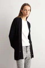 Ruana negra de tejido de punto, con mangas largas y cordón ajustable en la cintura.