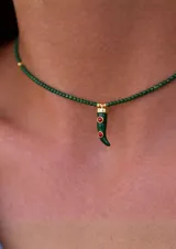 Collar tipo gargantilla compuesto por pequeñas cuentas verdes, con un dije colgante en forma de cuerno o chile, de color verde esmaltado con detalles circulares rojos y terminaciones doradas.