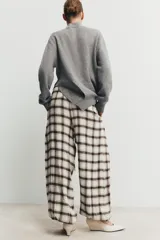 Pantalón bombacho de tiro alto con estampado de cuadros en tonos crudo y marrón. Presenta cintura elástica ajustable con cordón y bajos elásticos.