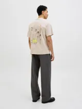 Remera color crema de corte recto y mangas cortas, con cuello redondo. Estampado en la espalda con un dibujo de una calle con edificios, palmeras y un auto amarillo.