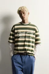 Camiseta relaxed fit de manga corta, con cuello redondo en rib a tono y diseño a rayas horizontales en tonos verde militar, blanco y mostaza. Cuenta con estampación frontal de texto a contraste.