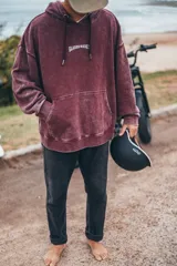 Hoodie de corte boxy fit en color bordó con efecto lavado. Presenta una estampa gráfica en la espalda con motivos playeros, palmeras y el texto 'Classy Waves'.