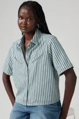 Camisa de denim a rayas verticales verdes y blancas, con cuello clásico, manga corta y cierre frontal con botones.