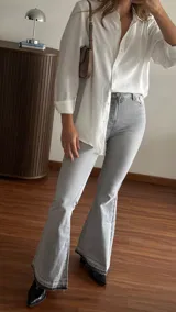 Jean Oxford de tiro medio-alto color gris lavado, con calce ajustado en la parte superior y botamanga acampanada con detalles deshilachados. Confeccionado en denim elastizado.