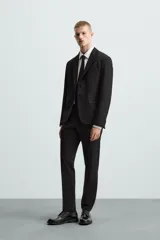 Blazer slim fit de color negro, confeccionada en tejido con viscosa. Presenta cuello con solapas de muesca, cierre frontal con botones, bolsillo de vivo en el pecho y bolsillos de solapa en la cadera.