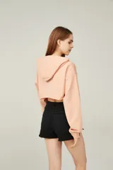 Buzo color durazno, corto, con capucha y mangas largas.