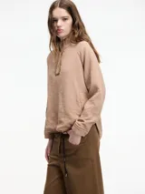 Sobrecamisa color beige, confeccionada en algodón texturizado (tipo guateado o nido de abeja), con cuello alto abotonado y mangas raglán.